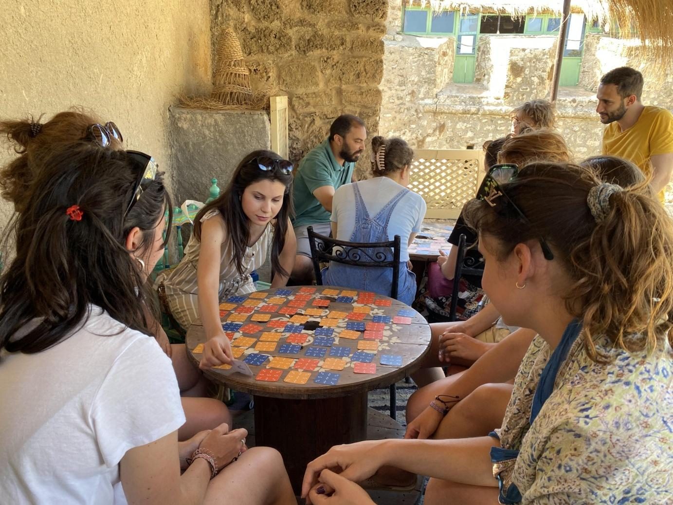 Enfants réunis autour d'un plateau de jeu en carreaux de céramique lors d'un atelier ECUME
