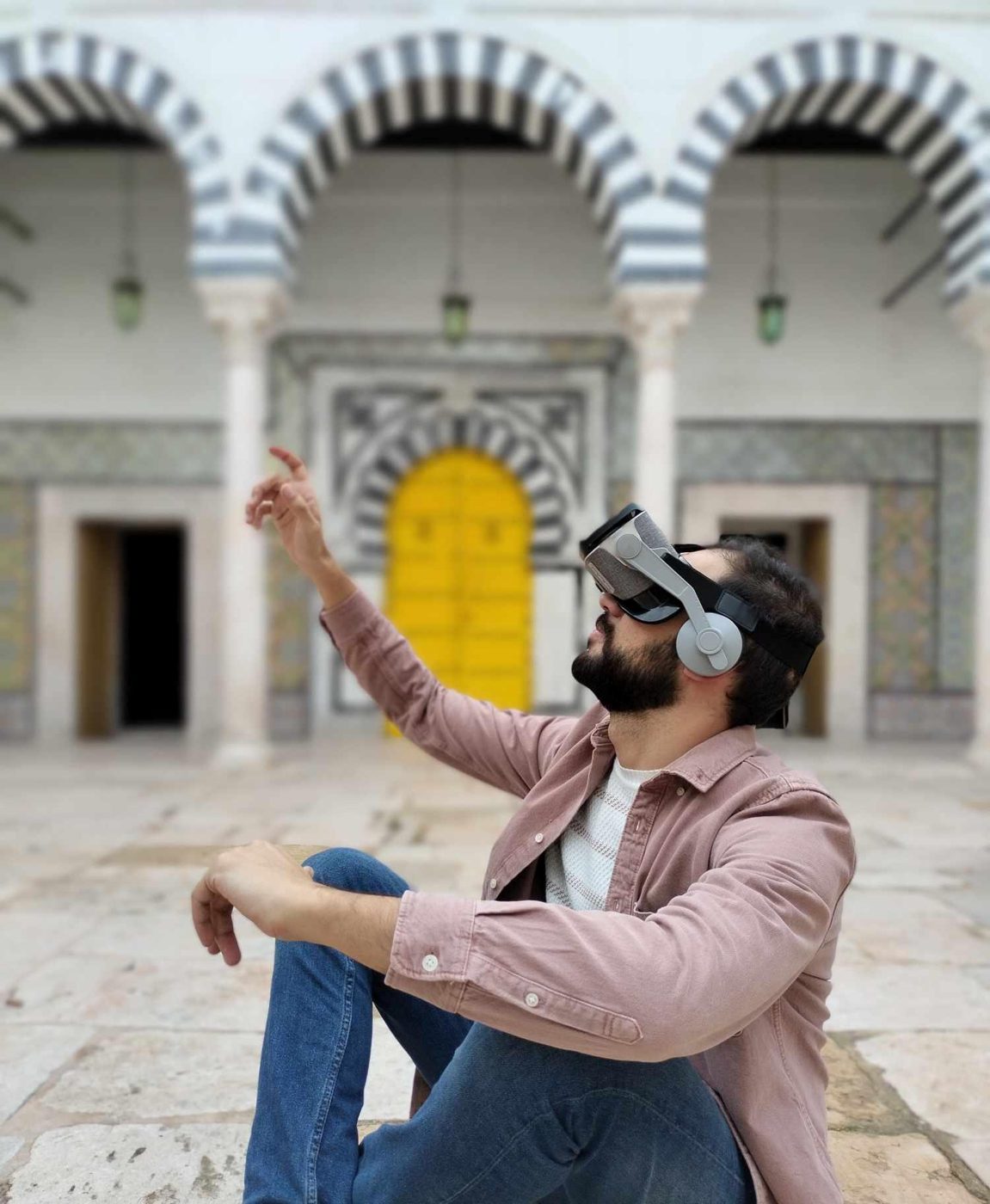 Visiteur équipé d'un casque de réalité virtuelle dans un patio tunisien orné de céramique